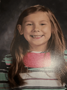 a young girl in a striped shirt smiles for a picture