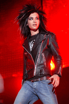 a man in a black leather jacket and blue jeans