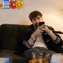 a young man is sitting on a couch looking at his phone .