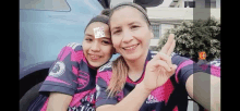 a woman and a girl are posing for a selfie while wearing pink jerseys .