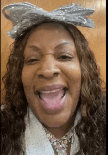 a woman wearing a bow on her head is sticking her tongue out .