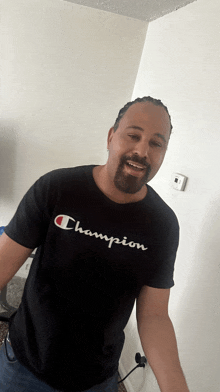 a man wearing a black champion t-shirt smiles for the camera