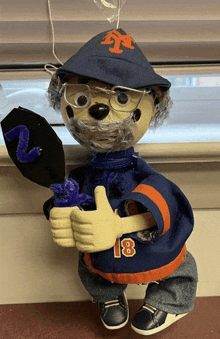 a stuffed animal wearing a ny hat and number 18 jersey