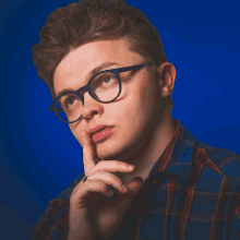 a man wearing glasses and a plaid shirt is thinking