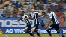 a group of soccer players are celebrating a goal in front of a sign that says " ao vivo "