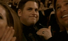 a man in a tuxedo is giving a thumbs up in a crowd