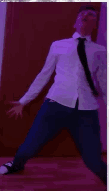 a man in a white shirt and tie is dancing in a room with purple lights