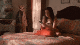 a woman is sitting on a bed looking at her cell phone