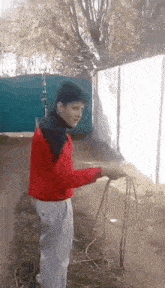 a boy in a red jacket is holding a rope in his hand