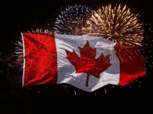 a canadian flag is flying in front of fireworks