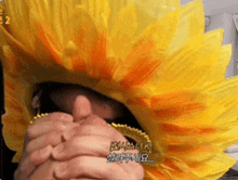 a person wearing a yellow and orange sunflower hat with chinese writing on it