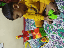 a boy in a yellow shirt is playing with toys