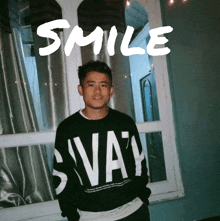 a man wearing a black sweater with the word smile on it