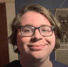 a young man wearing glasses and a blue shirt smiles