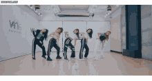 a group of girls are dancing in front of a wall that says wne
