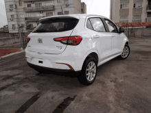 a white fiat car is parked in a parking lot in front of a building