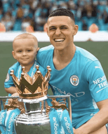 a man in a manchester city jersey holds a trophy next to a little boy