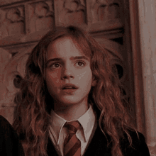 hermione granger from harry potter is wearing a red tie and a black jacket .