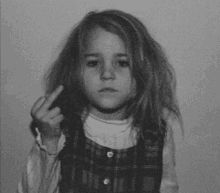 a little girl in a plaid dress is giving the middle finger