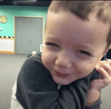 a little boy is smiling while being held by a person in a room with a clock on the wall .