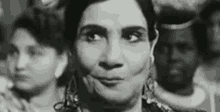 a black and white photo of a woman making a funny face in a crowd .