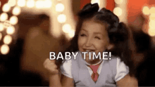 a little girl is smiling and saying `` baby time '' while wearing a tie .