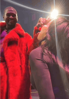 a man in a red fur coat is standing next to a woman in purple pants