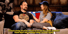 a man and a woman are sitting on a couch and the man is wearing a shirt that says ' strong arms '