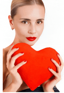 a woman with red lipstick is holding a red heart shaped pillow