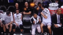 a group of basketball players sitting on a bench with one wearing a jersey that says world cup on it