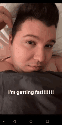 a man is laying in bed with the words " i 'm getting fat " on the bottom