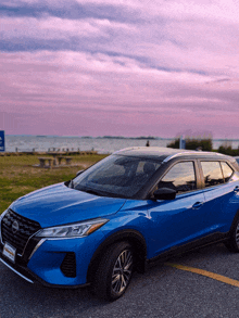 a blue nissan car is parked in a parking lot near the water