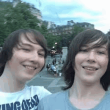 two young men are standing next to each other and smiling for the camera .