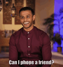 a man in a maroon shirt is smiling and asking " can i phone a friend ? "