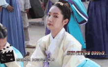 a woman in a traditional korean dress is sitting in front of a sign that says making film # 2