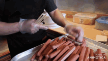 a tray of hot dogs is being prepared by a person with gloves and the words made in animotica on the bottom