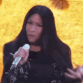a woman with long black hair is holding a microphone and making a funny face