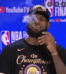 a basketball player is smoking a cigarette while wearing a championship ring .