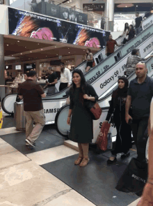 a woman in a black dress walks down an escalator with a galaxy s9 advertisement on it