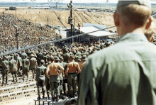 a large group of soldiers are standing in a stadium watching a concert .