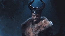 a man wearing a horned hat and a fur coat is smiling .