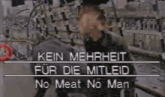 a man stands in front of a sign that says kein mehrheit fur die mitleid no meat no man