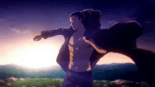 a man is standing in a field with his arms outstretched in front of a sunset .