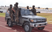 a group of soldiers are standing on top of a toyota truck on a track .