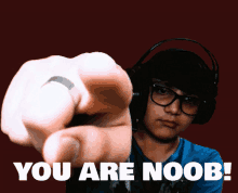 a man wearing headphones points at the camera with the words you are noob