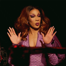 a woman in a purple dress holds her hands up