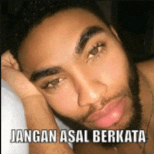 a man with a beard is laying on a bed with a caption that says jangan asal berkata