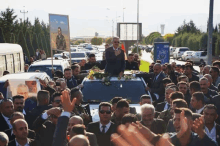 a man in sunglasses stands on the back of a car