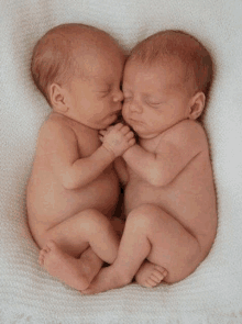 two newborn babies are laying next to each other on a white blanket