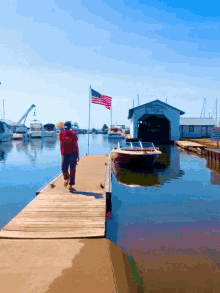 a man walks down a dock in front of a boat shed that says ' yacht & yacht ' on it